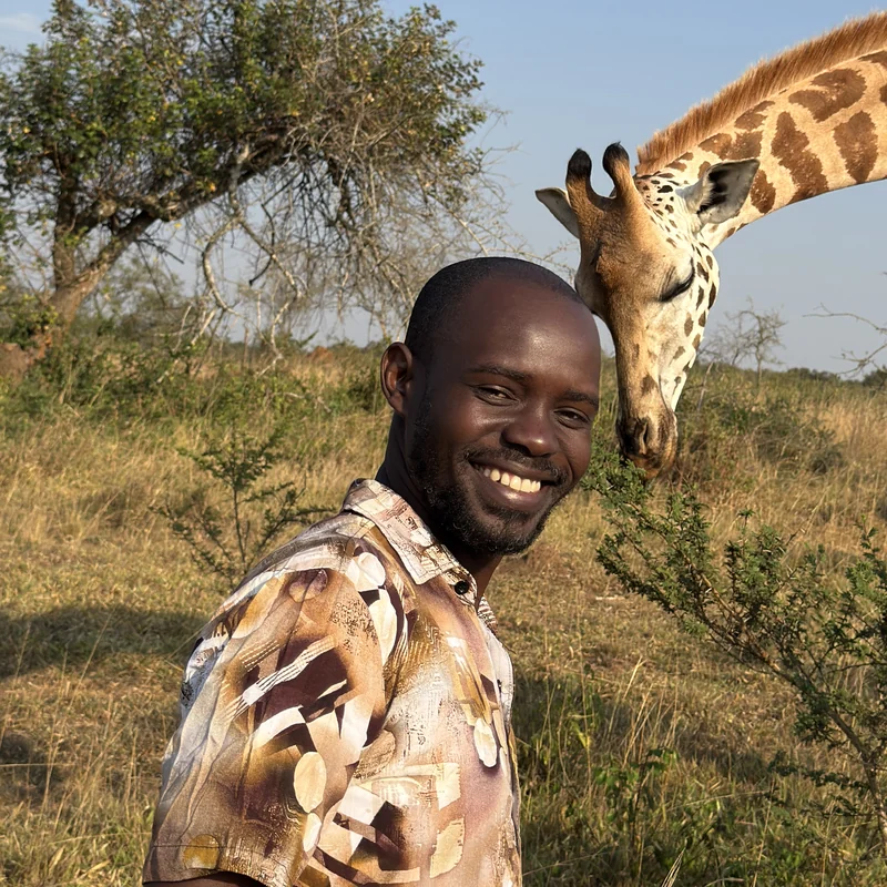 William Obia, Director of Orika Africa, with a giraffe on the savannah in Uganda
